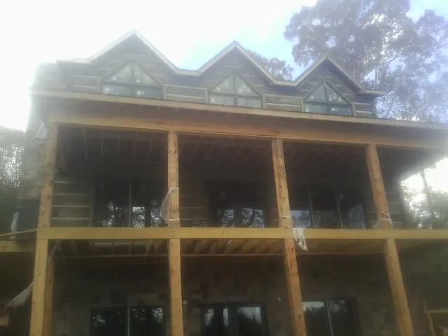 Dormers and porch framing on a large log home under construction — Roof Coating work by our crew in Madisonville